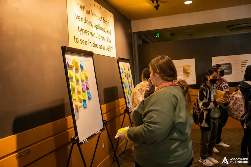student adding sticky note to board